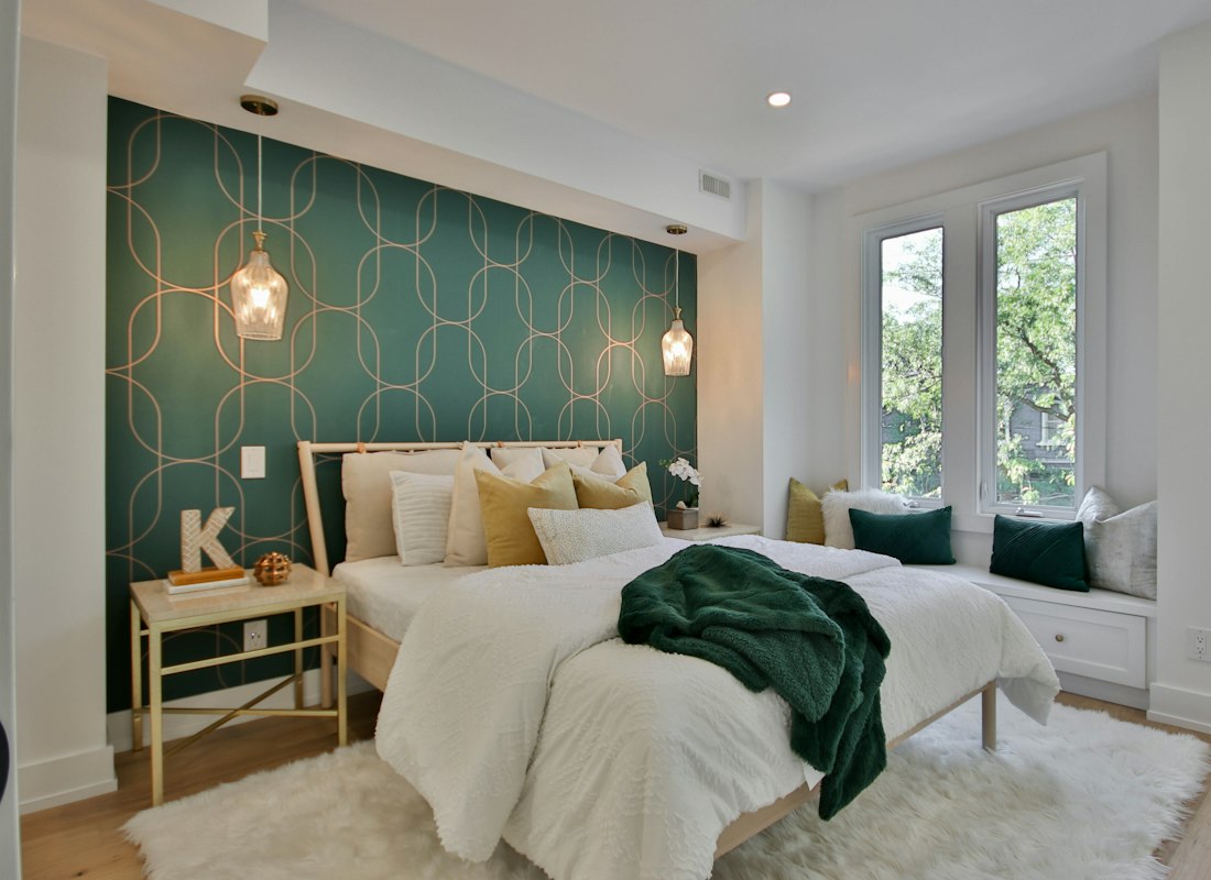 Bedroom with white bedding textiles against a green accent wall
