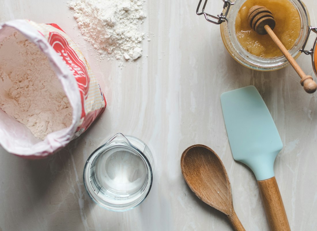 Wooden ladle and spatula laid out on a pale timber surface